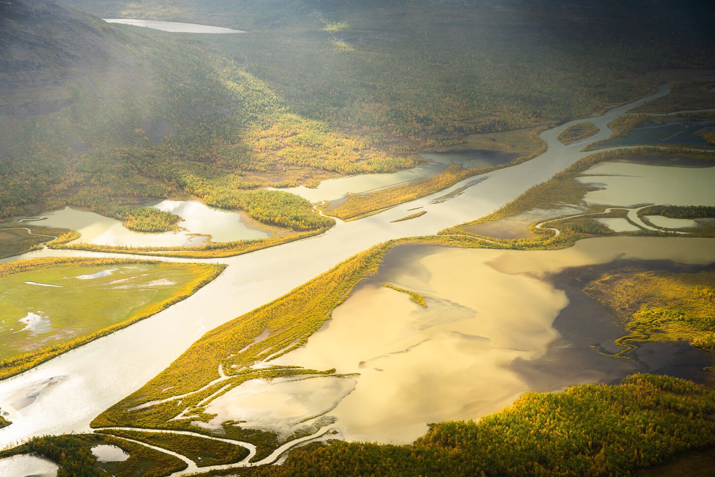 Detail of a river in the Sarek National Park lit by the sun through a break in the clouds.