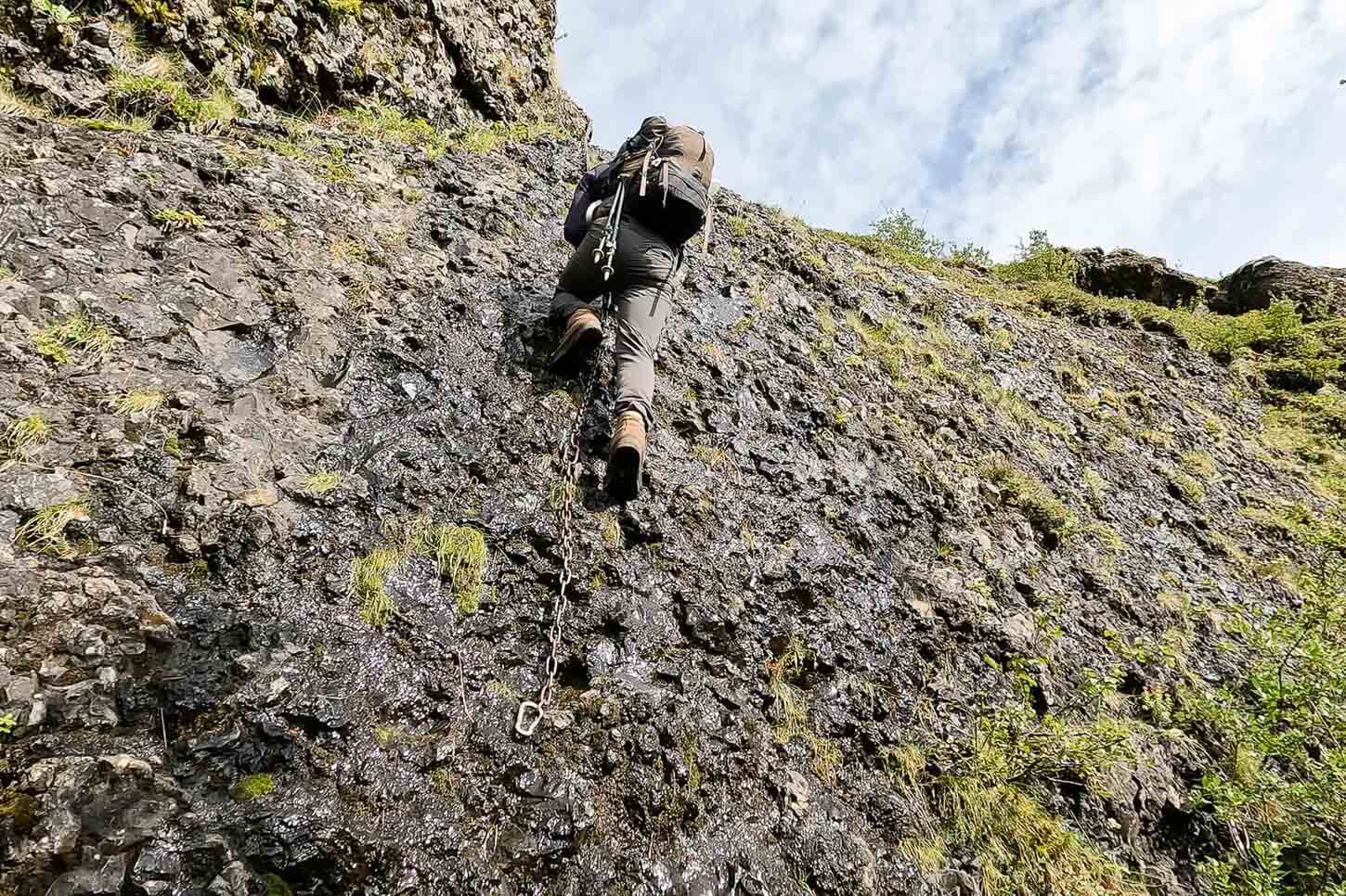 HIker climbing a wall on the teail to the Hvítárfoss and Núpsárfoss viewpoint