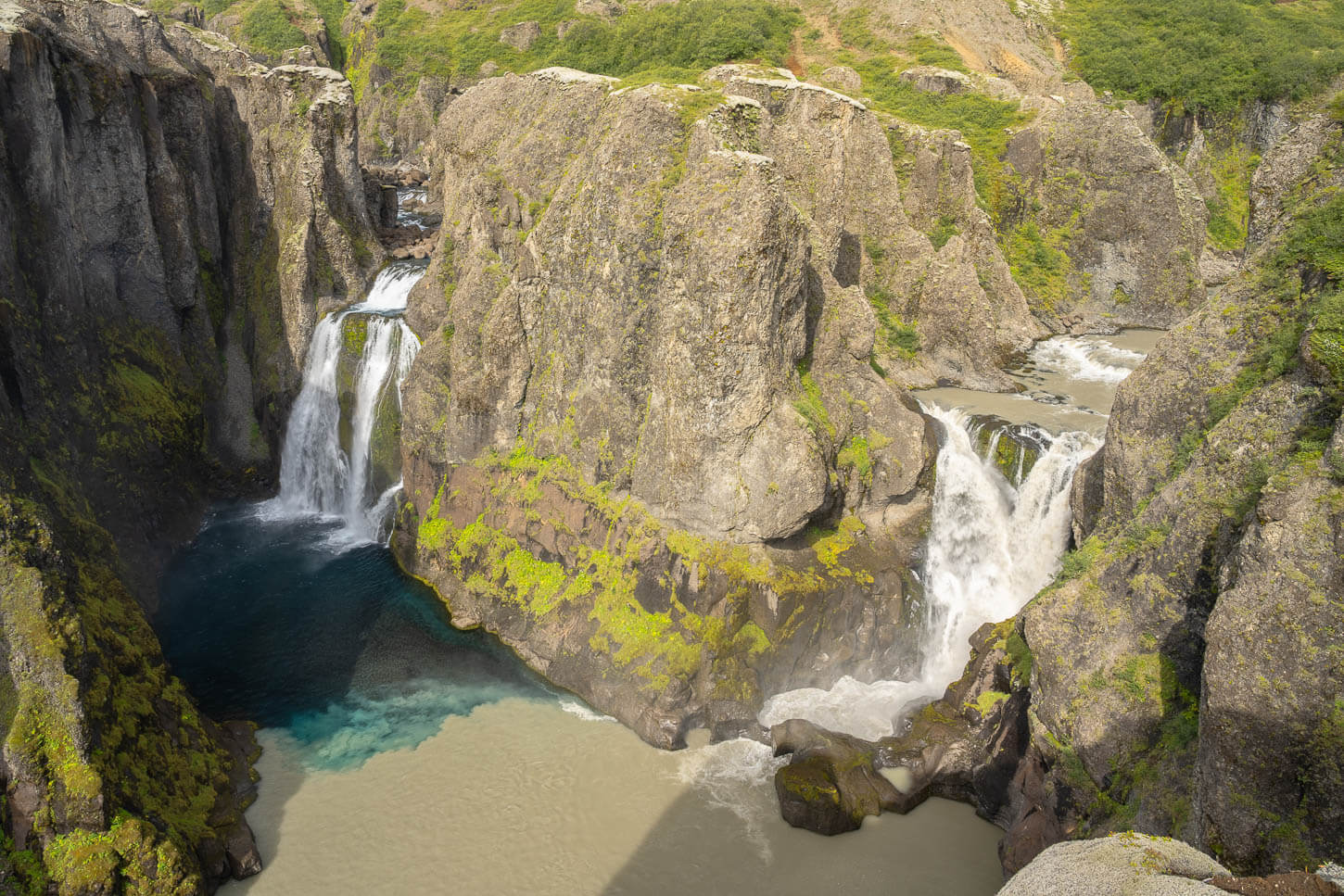 Hvitárfoss and Núpsárfoss, two twin waterfalls merging into the same pool of water with different mixing colors.