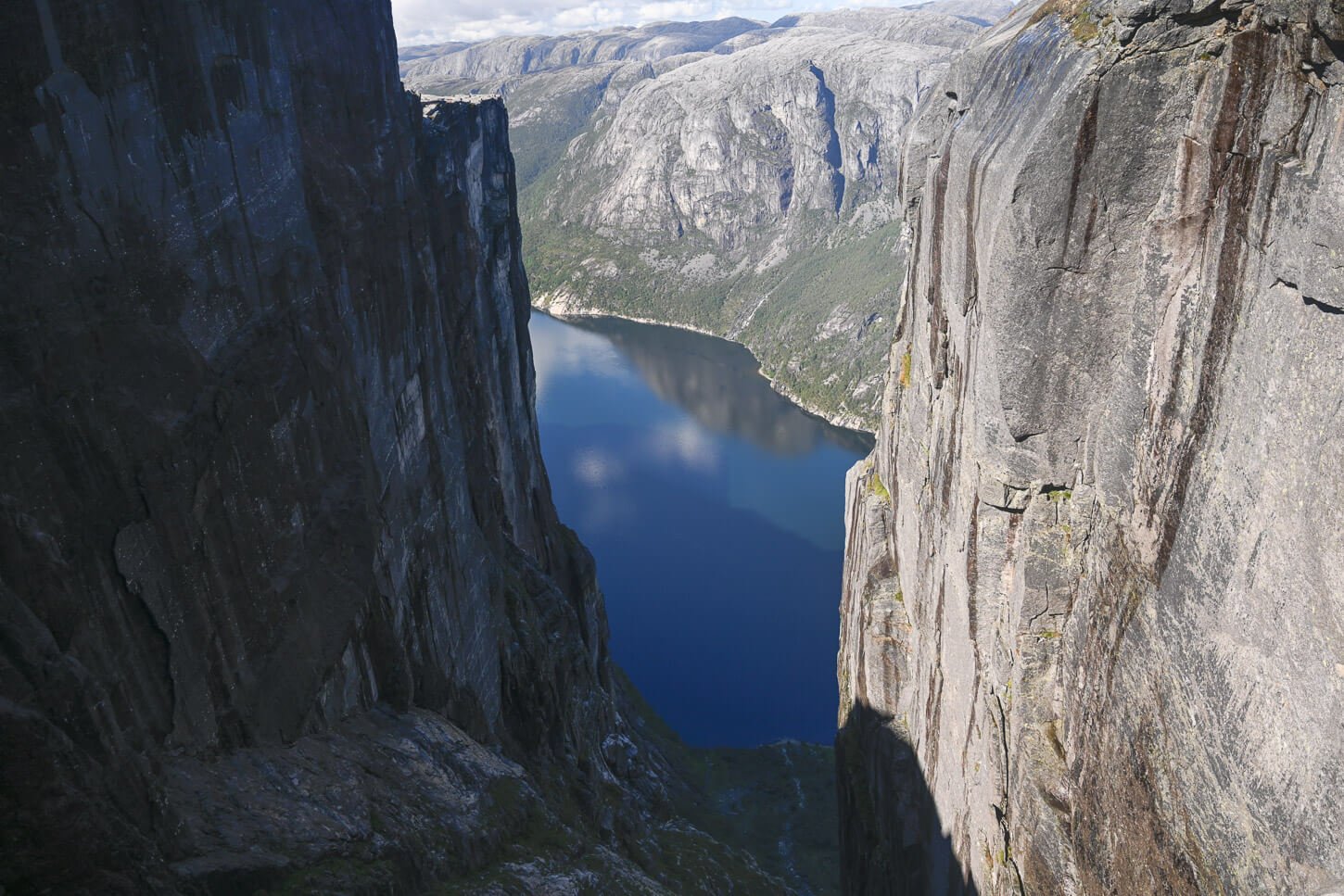 View of the landscape standing on top of the boulder Kjeragbolten, with view of the Lysefjord between two vertical rockfaces.
