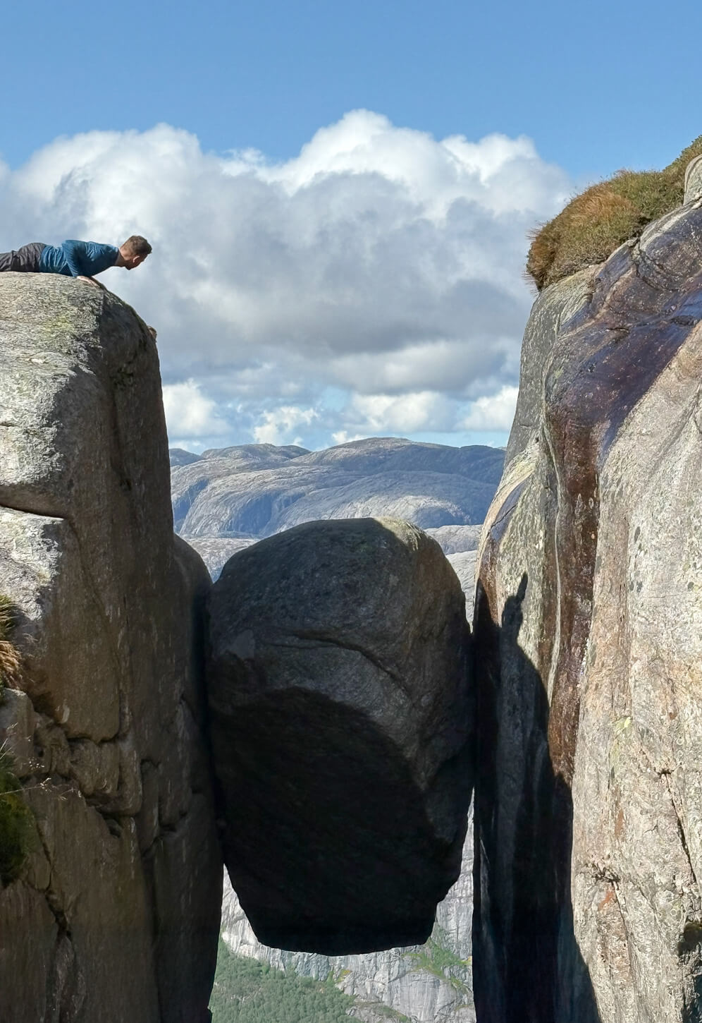 Hiker worriedly looking at the dangerous Kjerabolten boulder