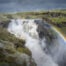Lambhagafoss, a hidden waterfall in Iceland surrounded by green moss with a rainbow in front of it.