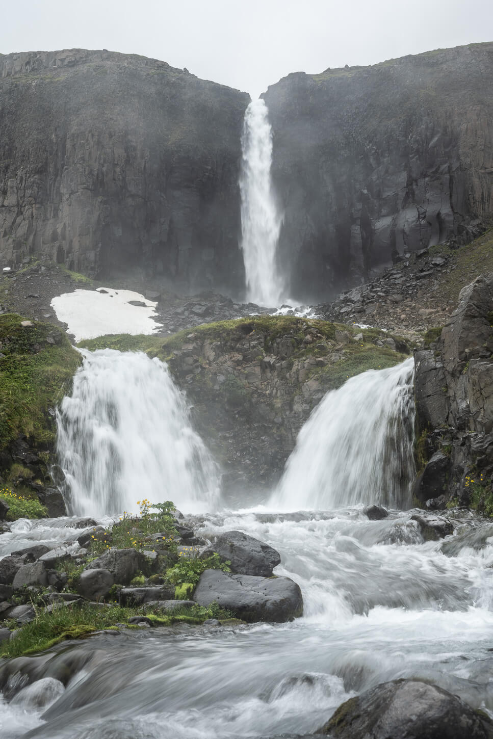 View of Mongufoss, a waterfall with two. more mirroring waterfalls in front of it.