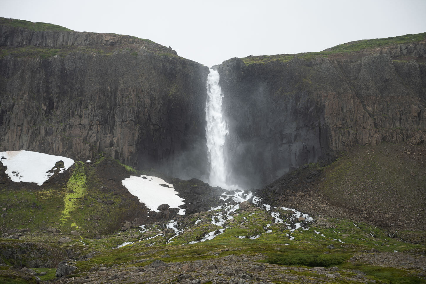 Mongufoss a waterfall in the westfjords under a grey sky, typical of Iceland.