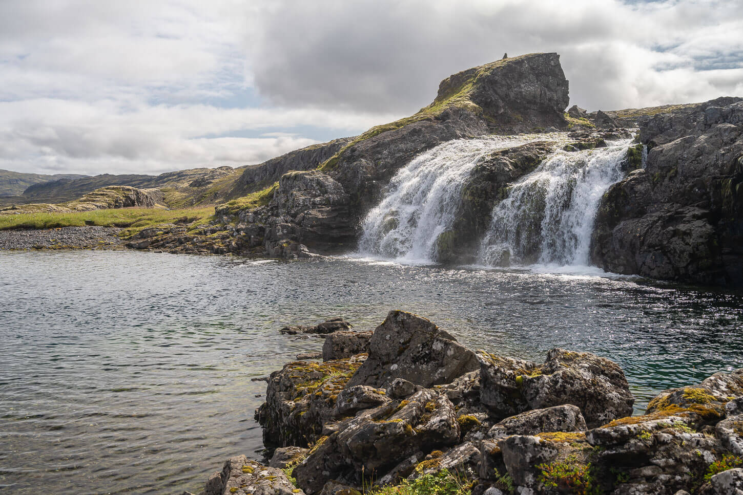 Hvalarfoss a double waterfall in the westfjords, falling in a pool of calm waterds.