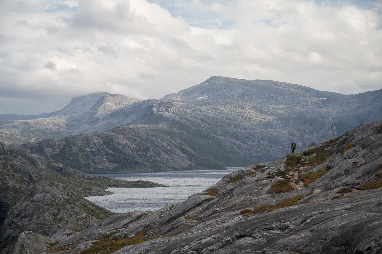A hiker in the Norwegian mountain, walking toward the lake Litlverivatnet.