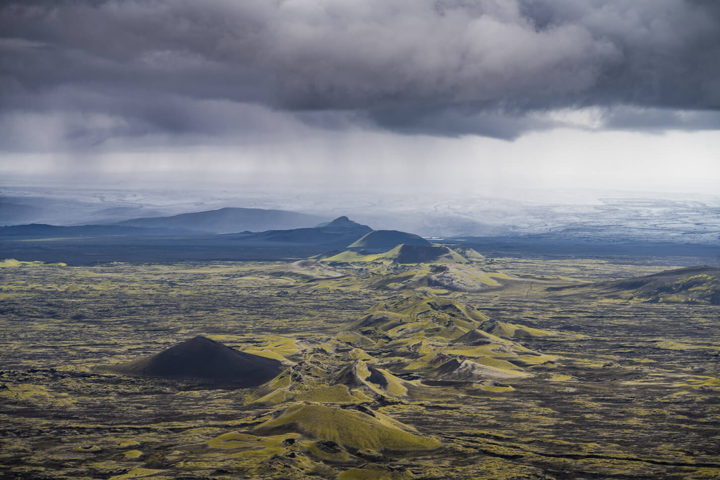 Row of craters to the Nort of Laki, with the Vatnajökull ice cap in the background, under a rainy, menacing sky.