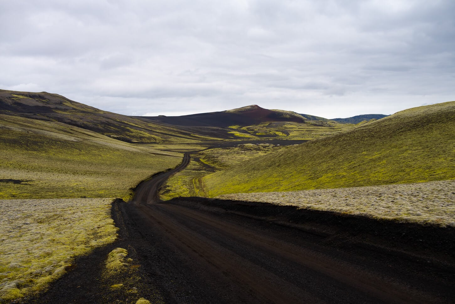 blakc sand road F207 surrounded by moss covered hill in the highlands of iceland.
