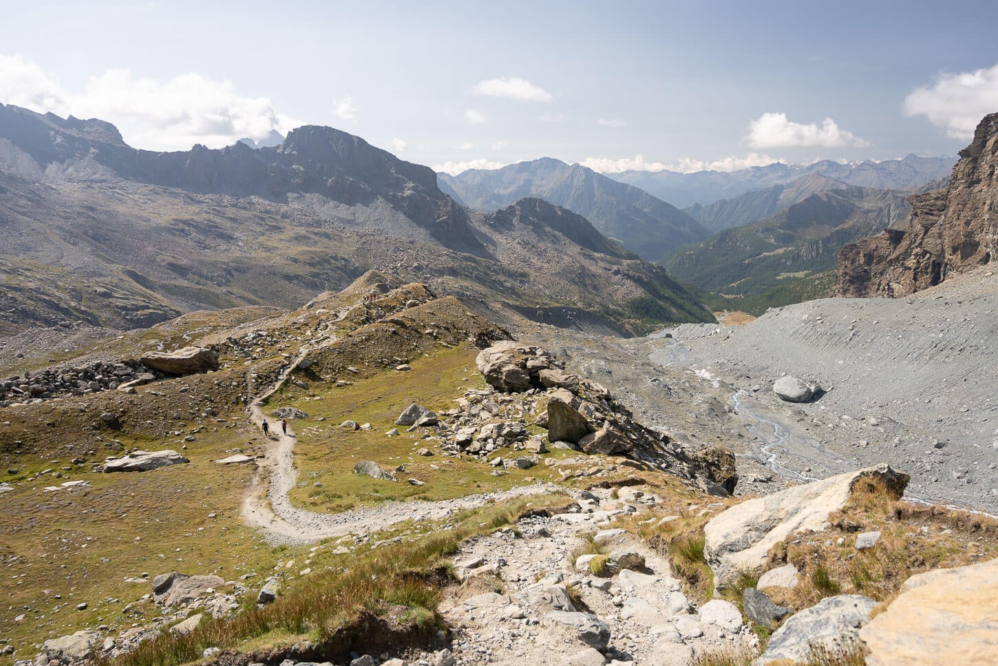 Sectino of the trail to Rifugio Mezzalama on the moraine, with several layers of mountains in the background.