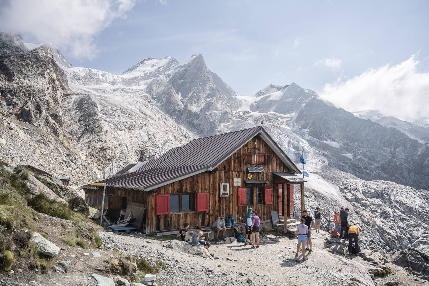 Rifugio Mezzalama with several people relaxing or watching the landscape after a long and strenuous hike,