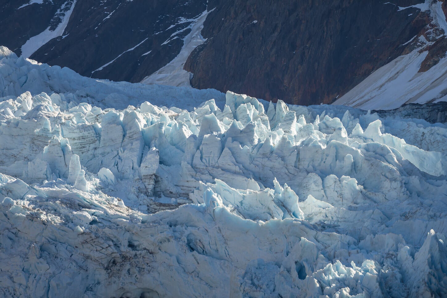 Seracs of a glacier partly lit by the sun light.
