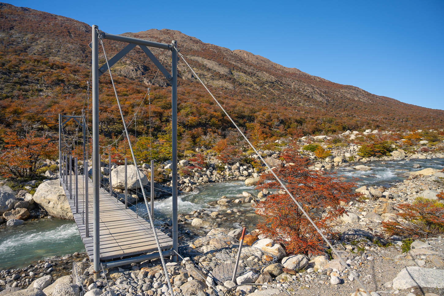 small pedestrian suspension bridge across a small creek in Patagonia