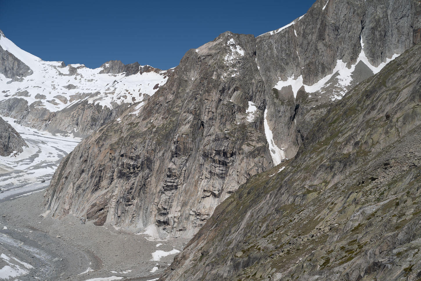 steep rocky mountains with the roof of a hut barely visible