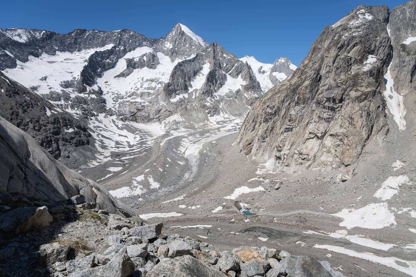Oberaletsch glacier and Beich Glacer merging point, a mountainous landscape with jagged peaks surrounding debris-covered glaciers, which requires hiking beyond the Oberaltsch hut.