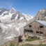 Oberaletsch Hut above a glacier valley on a sunny day, a location that makes a great day hike in the Swiss Alps.