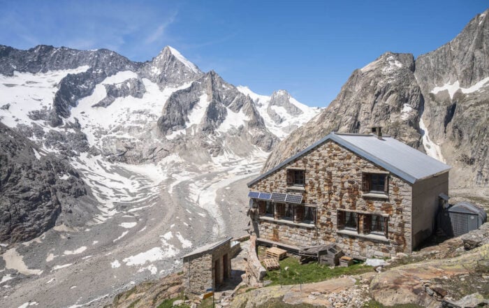 Oberaletsch Hut above a glacier valley on a sunny day, a location that makes a great day hike in the Swiss Alps.