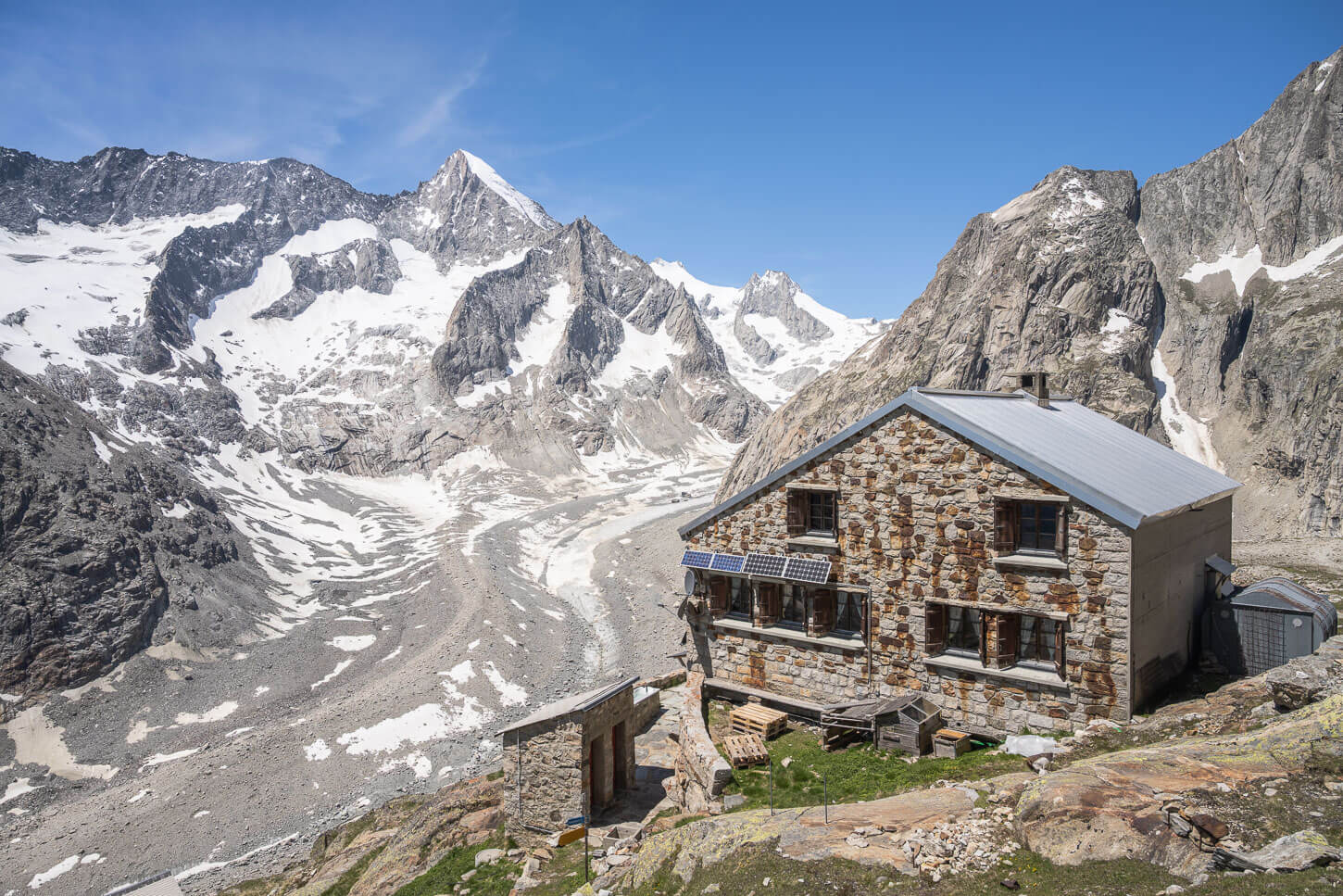 Oberaletsch Hut above a glacier valley on a sunny day, a location that makes a great day hike in the Swiss Alps.