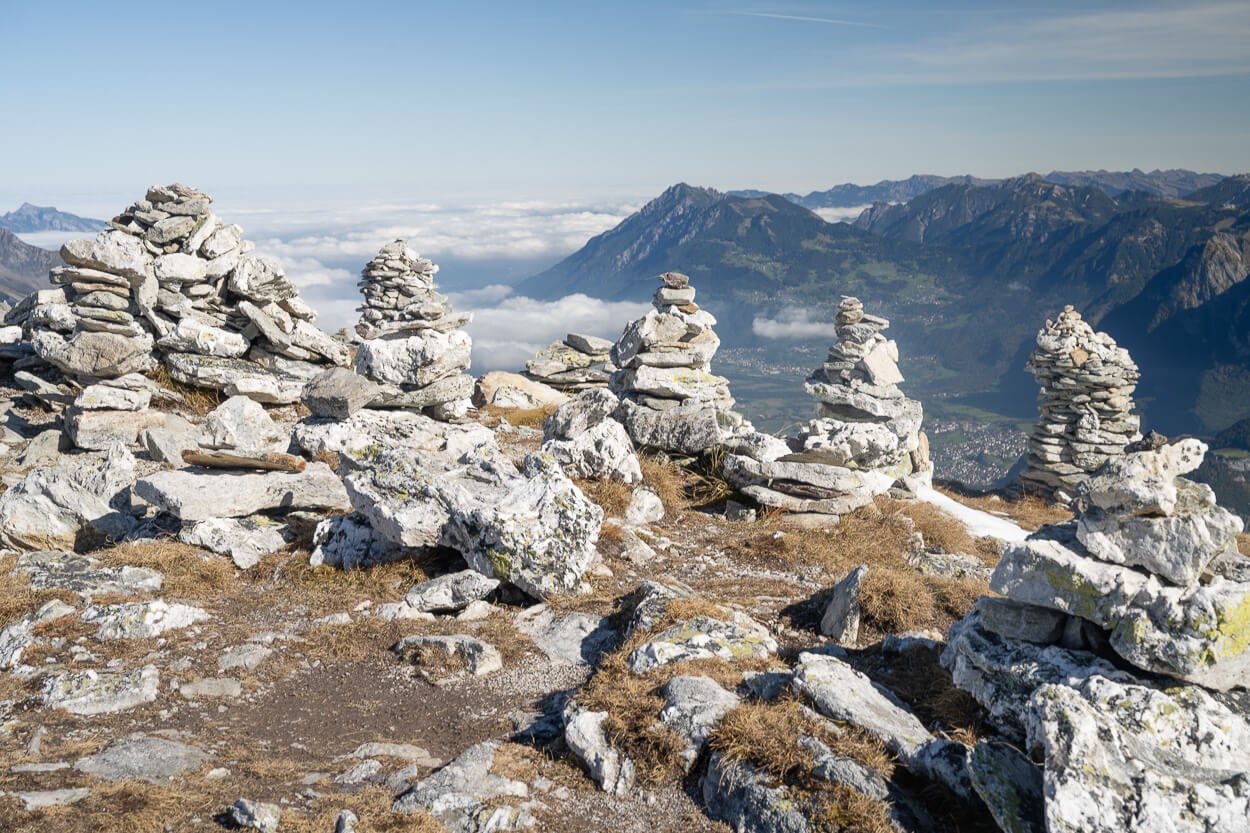 Large cainrs on the Pizol file lakes hike, called Steinmannli, made with stones from the area, overlooking a valley far down below.