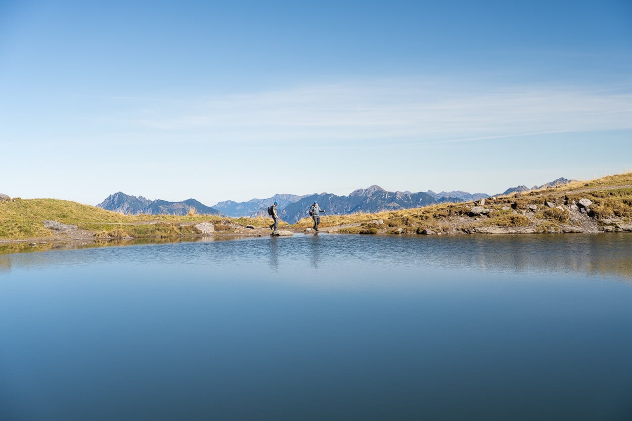 Hikers walking next to Baschalvasee, on a sunny day with clear skies.