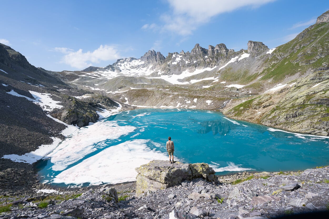 Hiker standing on a rock in front of Wildsee, the most popular lake on the Pizol Five Lakes Hike