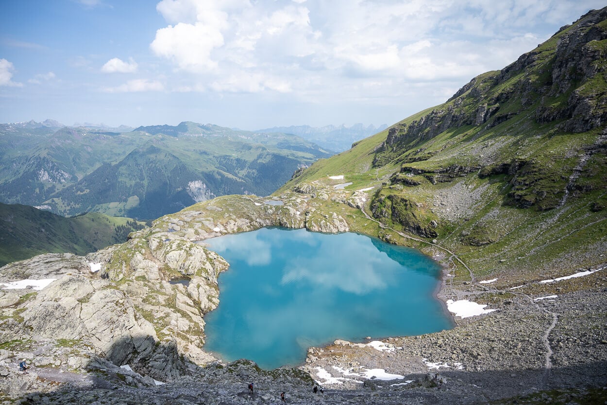 View of Schottensee frm above, with clouds refelctly in the turqoise waters of the lake, the second on on the Pizol Five Lakes Hike