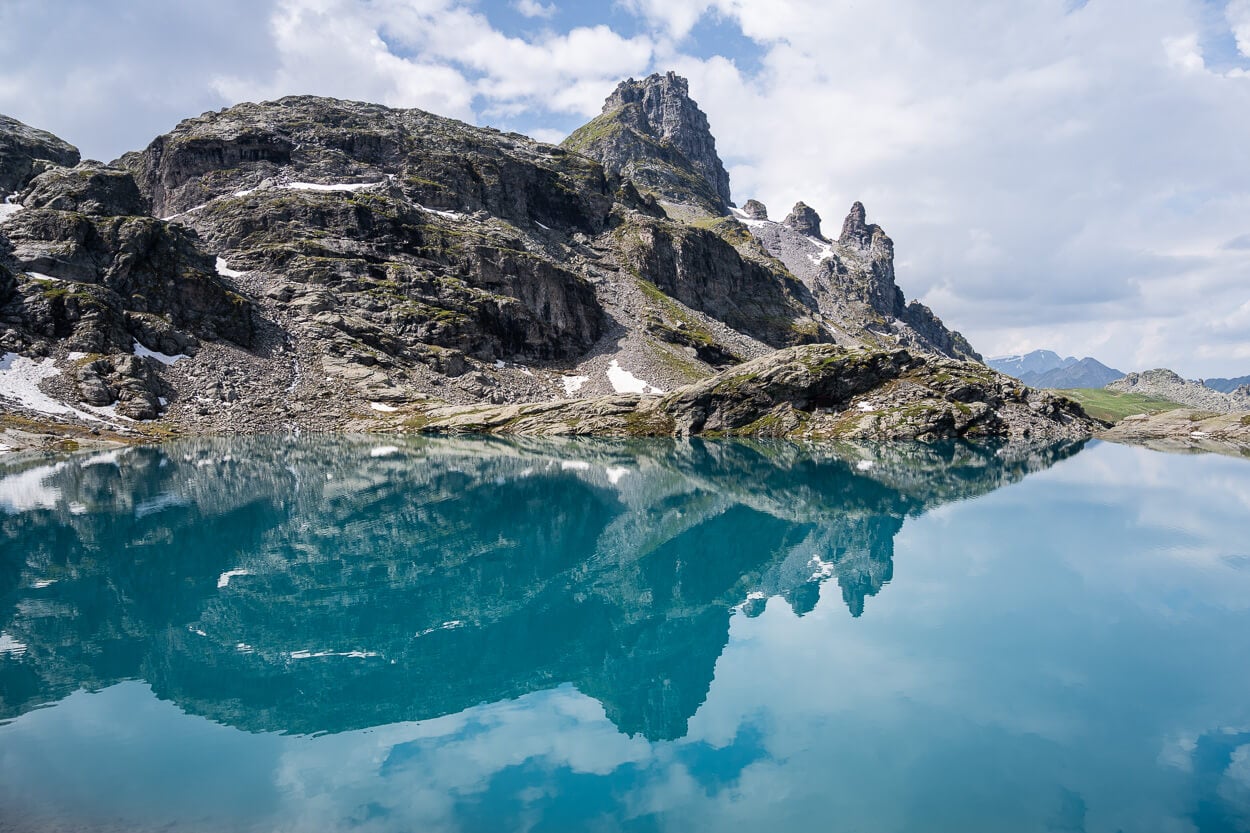 Rocks and mountain reflected in Schottensee, in a mirror-like reflection.
