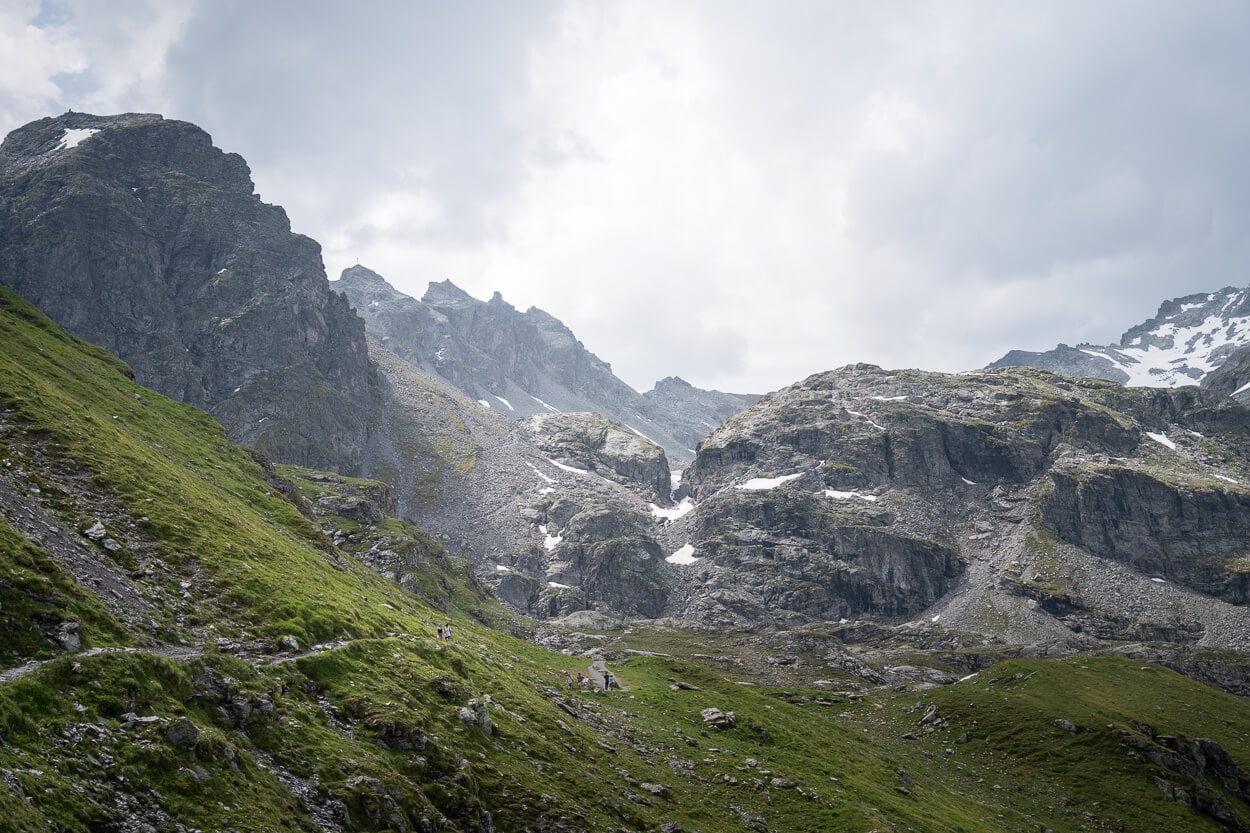 Dramatic alpine landscape with green slopes and rocky cliffs.