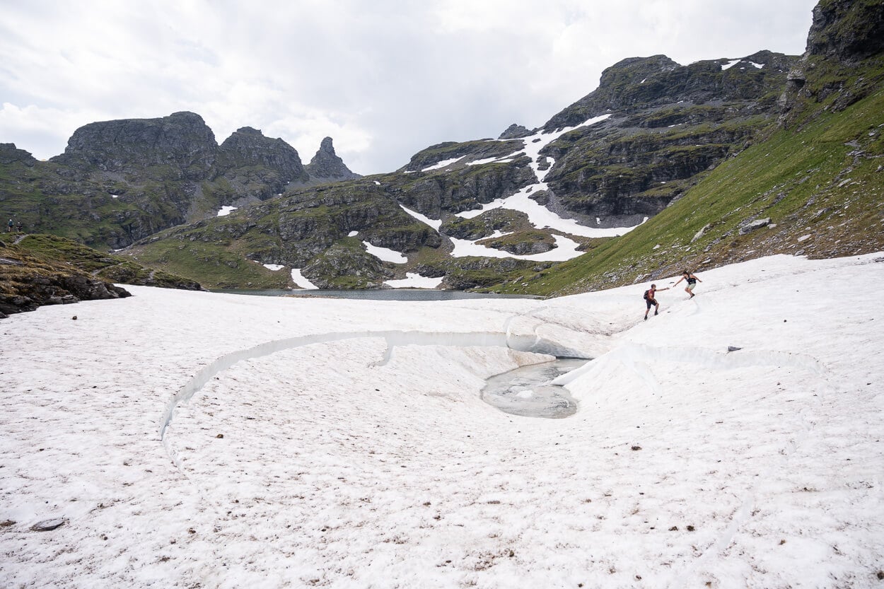 Hikers crossing a partly collapsed snow field.