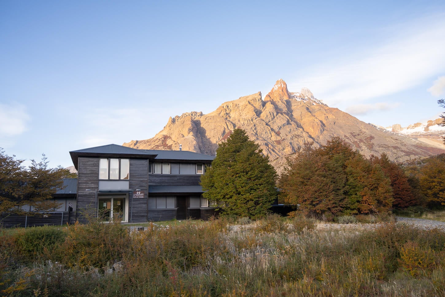 Los Huemules Nature Reserve Visitors Center on an ealy suny morning, with light shining on the rugged peaks in the background.
