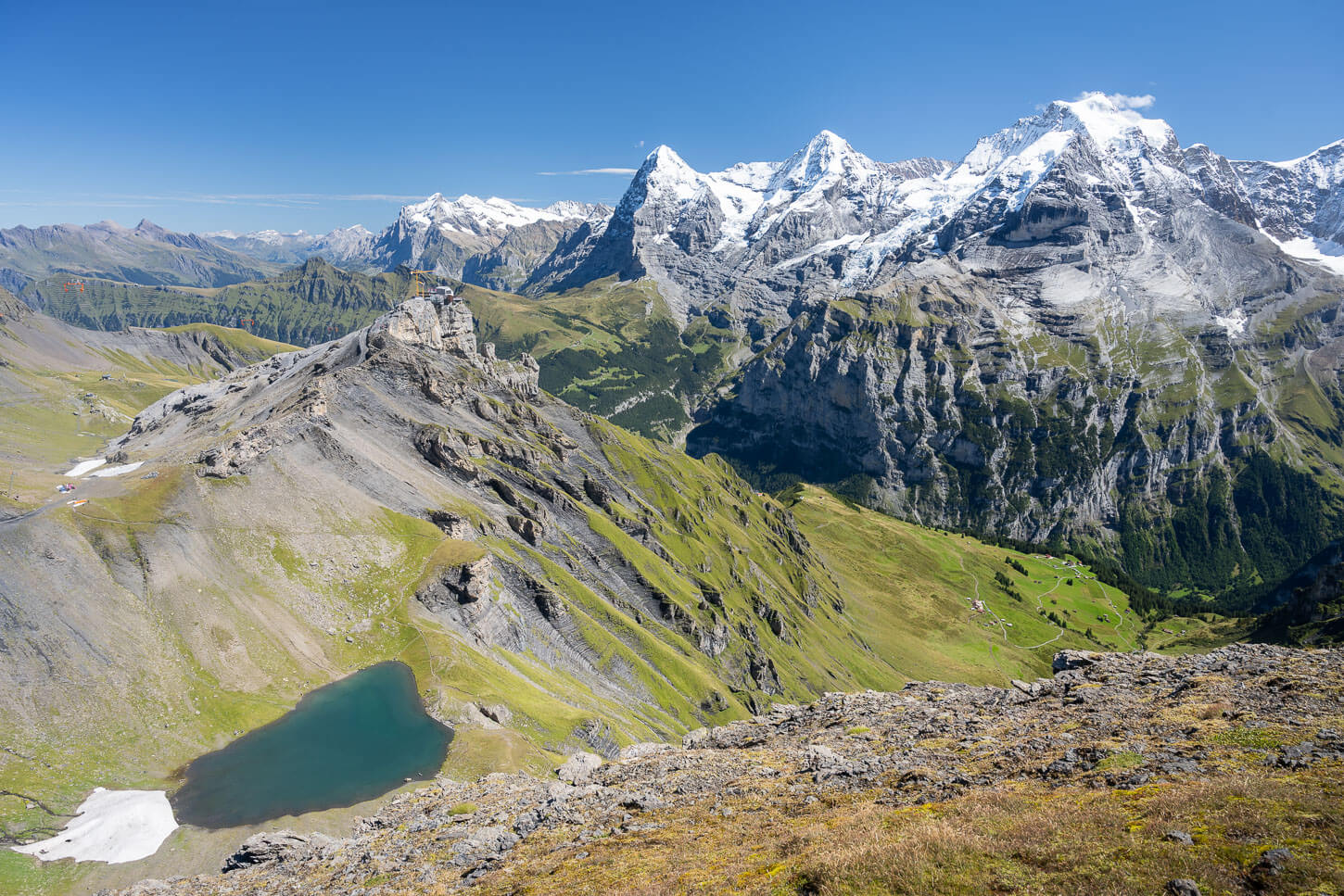Epic Landscape photo from a Hike to Schiltorn with the green Lauterbrunnen Valley below the towering peaks of the Eiger, the Mönch, and the Jungfrau.