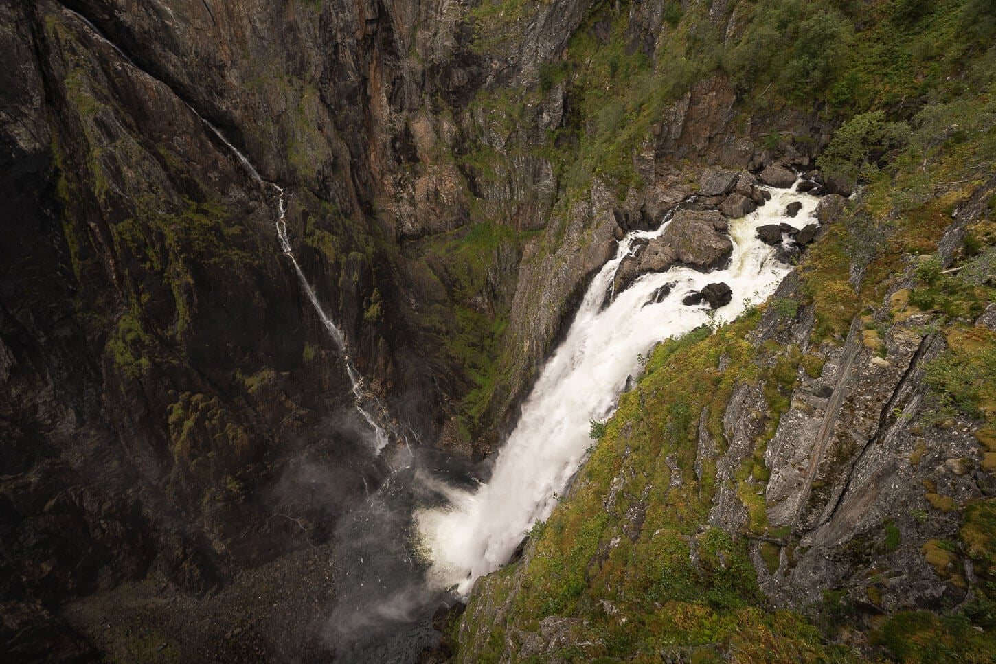 Vøringsfossen viewed from a viewpoint during a hike along the main path, almost directly above the waterfall, wher the powerful waterfall dramatically drops to the bottom of the valley.