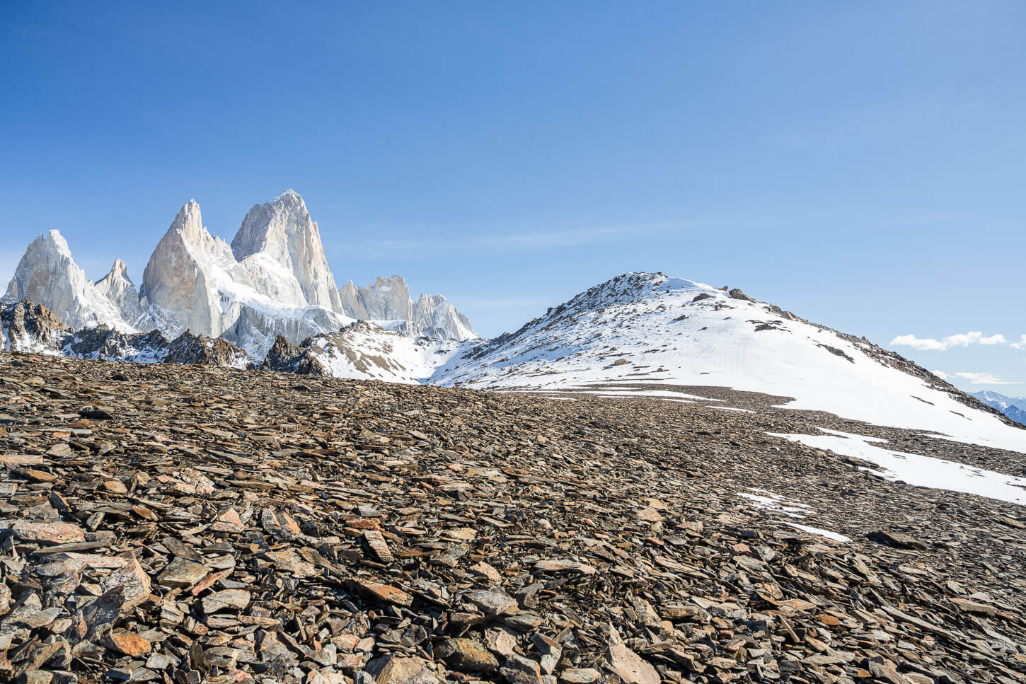 scree-covered slope with view of Loma the Las Pizarras summit in the distance, in front of Fitz Roy.