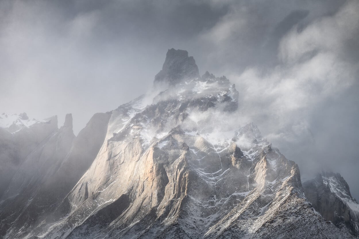 Cuernos del Paine under a dramatic and dynamic sky, with some sidelight shining on the mountain.