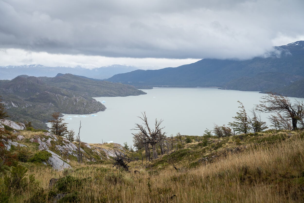 Lago Grey viewed from the Mirador Glacier Grey trail, under a sky with low clouds, with small icebergs floating in the lake.