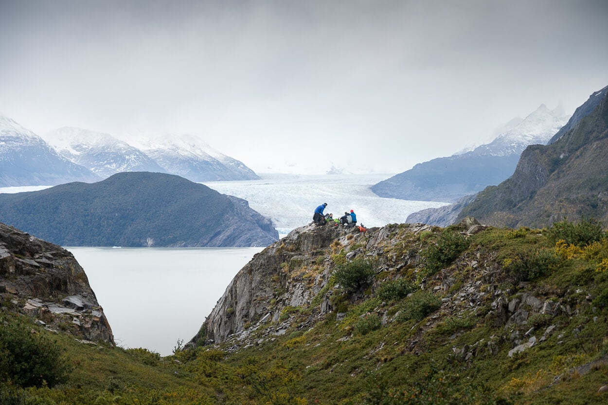 Hikers taking a break from their hike to Mirador Glacier Grey, and enjoy the landscape with the lake and glacier in the background.