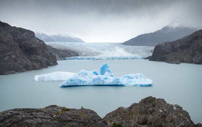Mirador Glacier Grey lookout on a cloudy day, with an iceberg floating in a lagoon in front of Glacier Gray, under a moody sky,