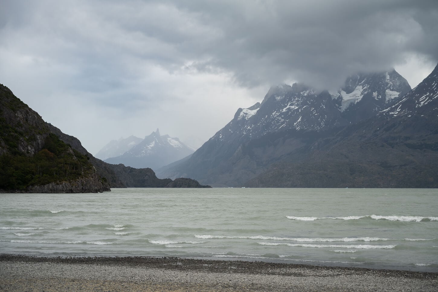 Lago Grey on a cloudy day, with rolling waves and the massive Torres del Paine mountains in the distance.