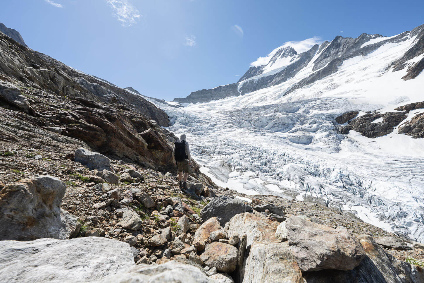 A hiker walking toward the upper Grindelwald glacier, on a sunny day ideal for a hike.