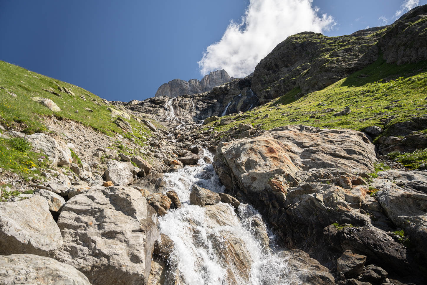 A small creek in the Alps, flowing down the steep, rocky mountainside.