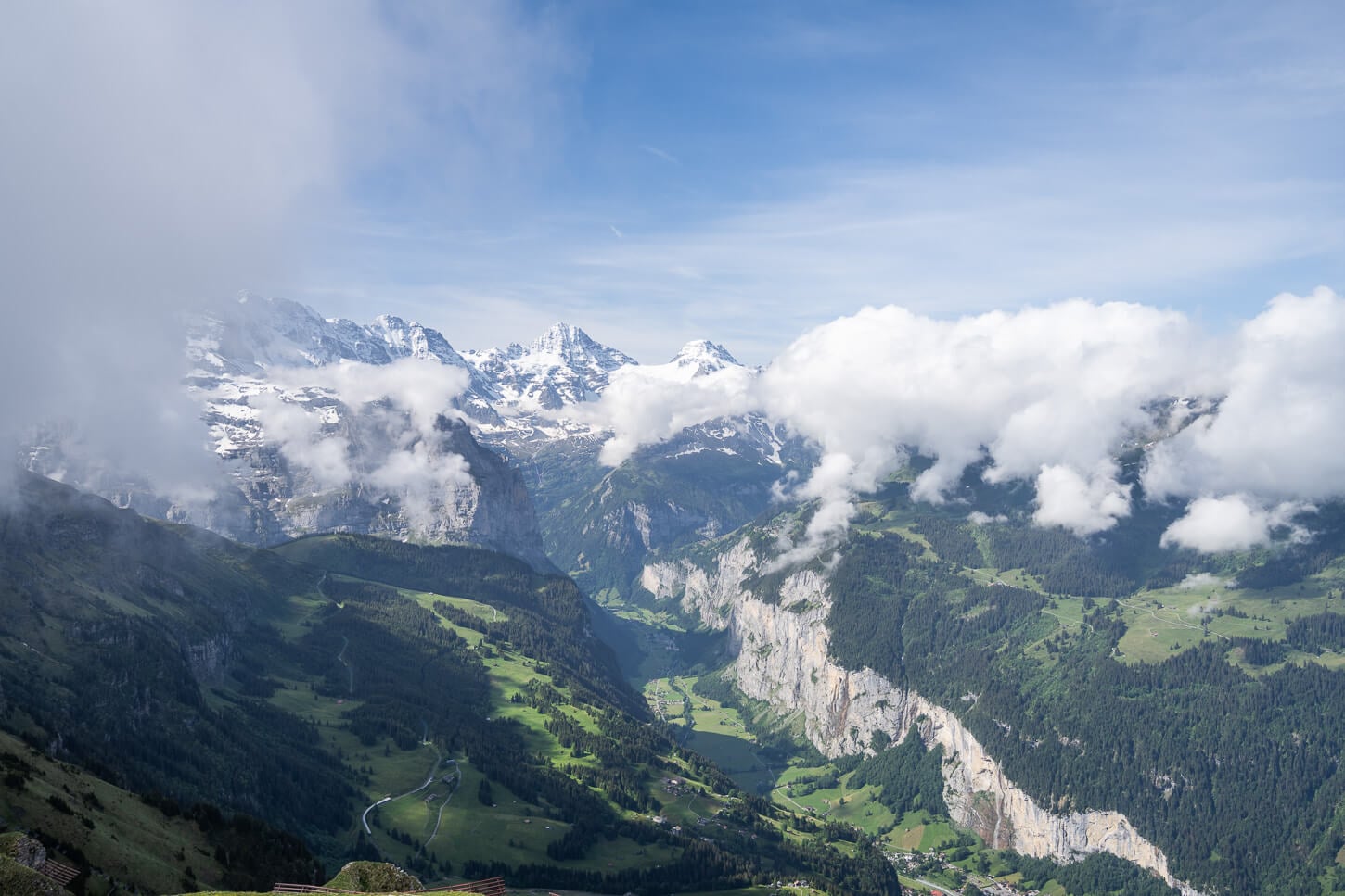 View of the lush green Lauterbrunnen valley at the end of the hike to Männlichen's observation deck, with mountains partly covered in clouds