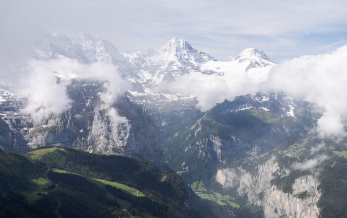 Panoramic View from the Wengen to Männlichen loop hike with open views of the green lauterbrunen valley un a sunny but partly cloudy day.