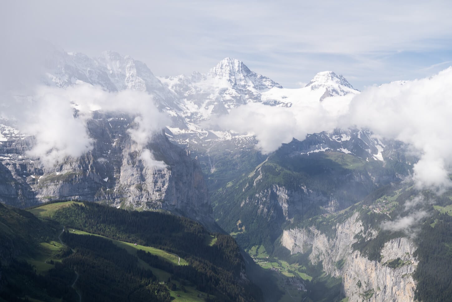 Panoramic View from the Wengen to Männlichen loop hike with open views of the green lauterbrunen valley un a sunny but partly cloudy day.