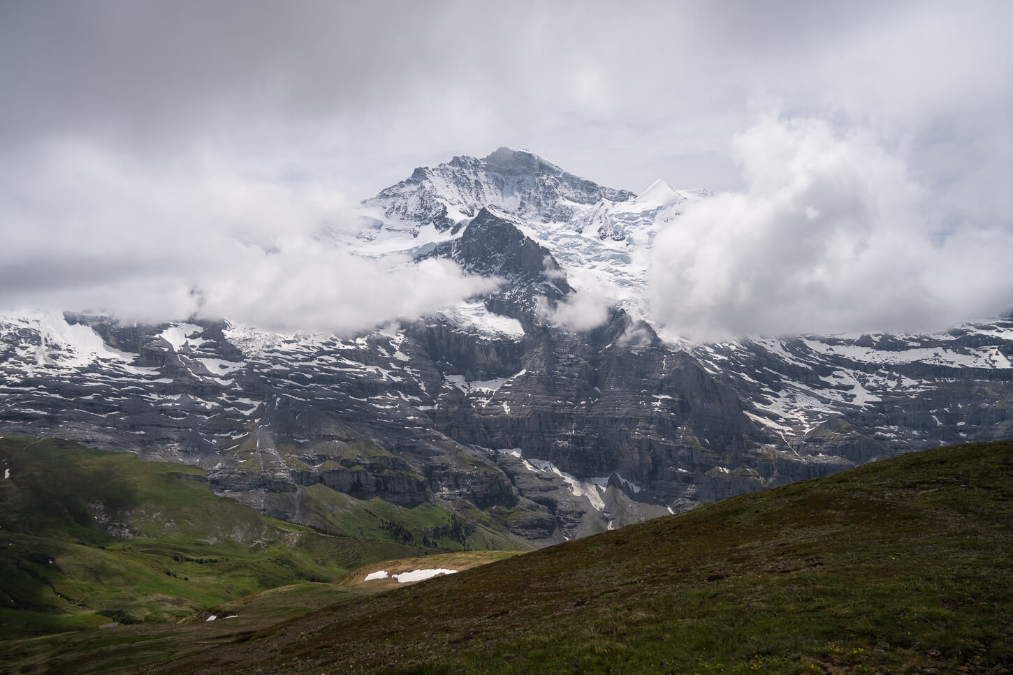 View of Jungfrau's summit and glaciers, partly covered in clouds, from the Panoramic trail between Männlichen and Kleine Scheidegg.
