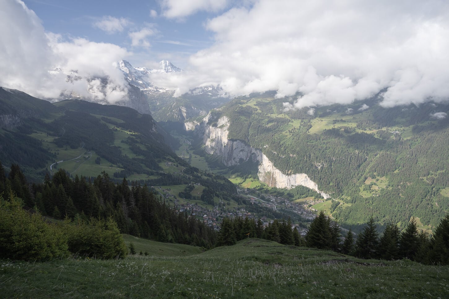 View of the Lauterbrunnen valley from the hike to Männlichen, with the sun shining on the western face of the valley on a partly cloudy morning.