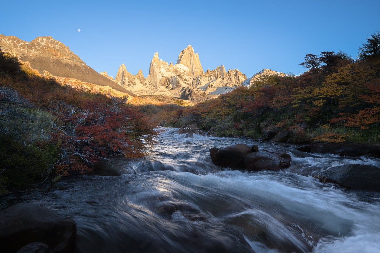 Streaming river in Patagonia during the golden hour, with the jagged mountain top of mount Fitz Roy in the background,