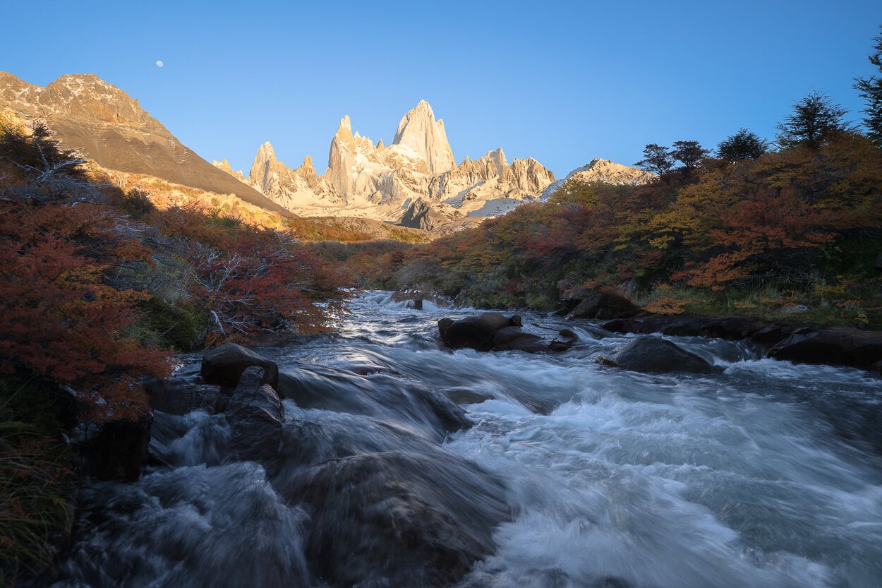 View of mount Fitz Roy in the background during the golden hour, with a streaming river in the foreground.