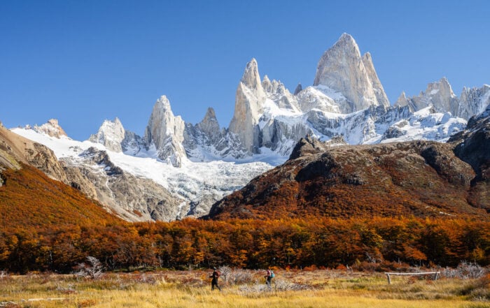 View of people on a Hike near El Chaltén, looking small compared to the towering Fitz Roy mountain above them.