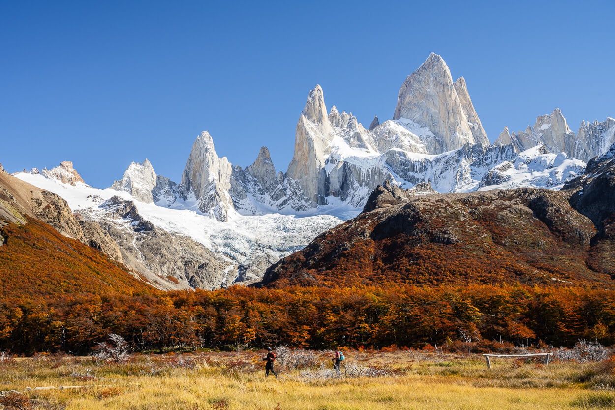 View of people on a Hike near El Chaltén, looking small compared to the towering Fitz Roy mountain above them.