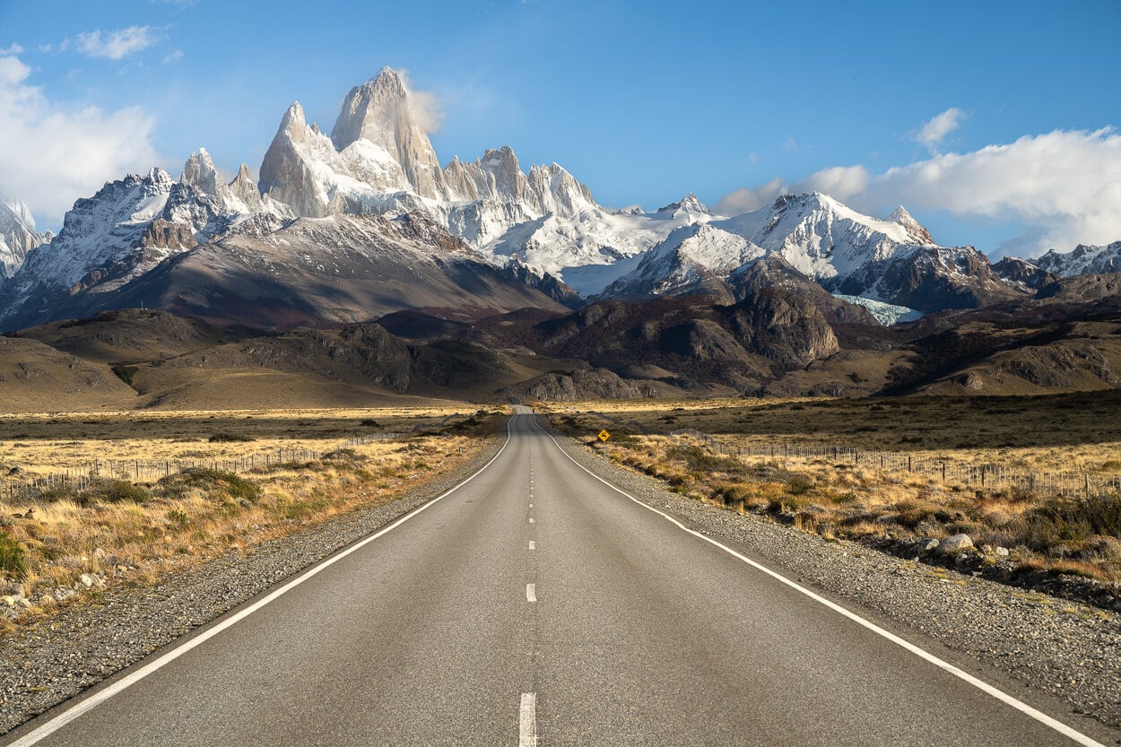 Road in Argentina leading intto a spectacular mountain range, the Fitz Roy massif, partly covered in snow.