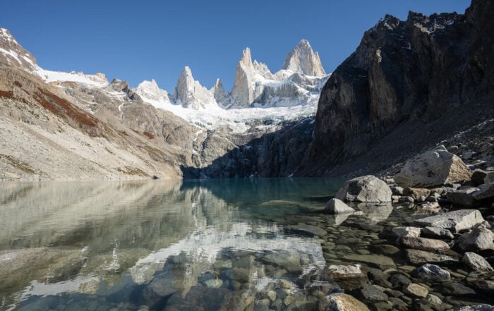 View of Laguna Sucia at the end of the hike, where the mountain Fitz Roy reflects in the waters of the lake on a sunny day with blue skies.